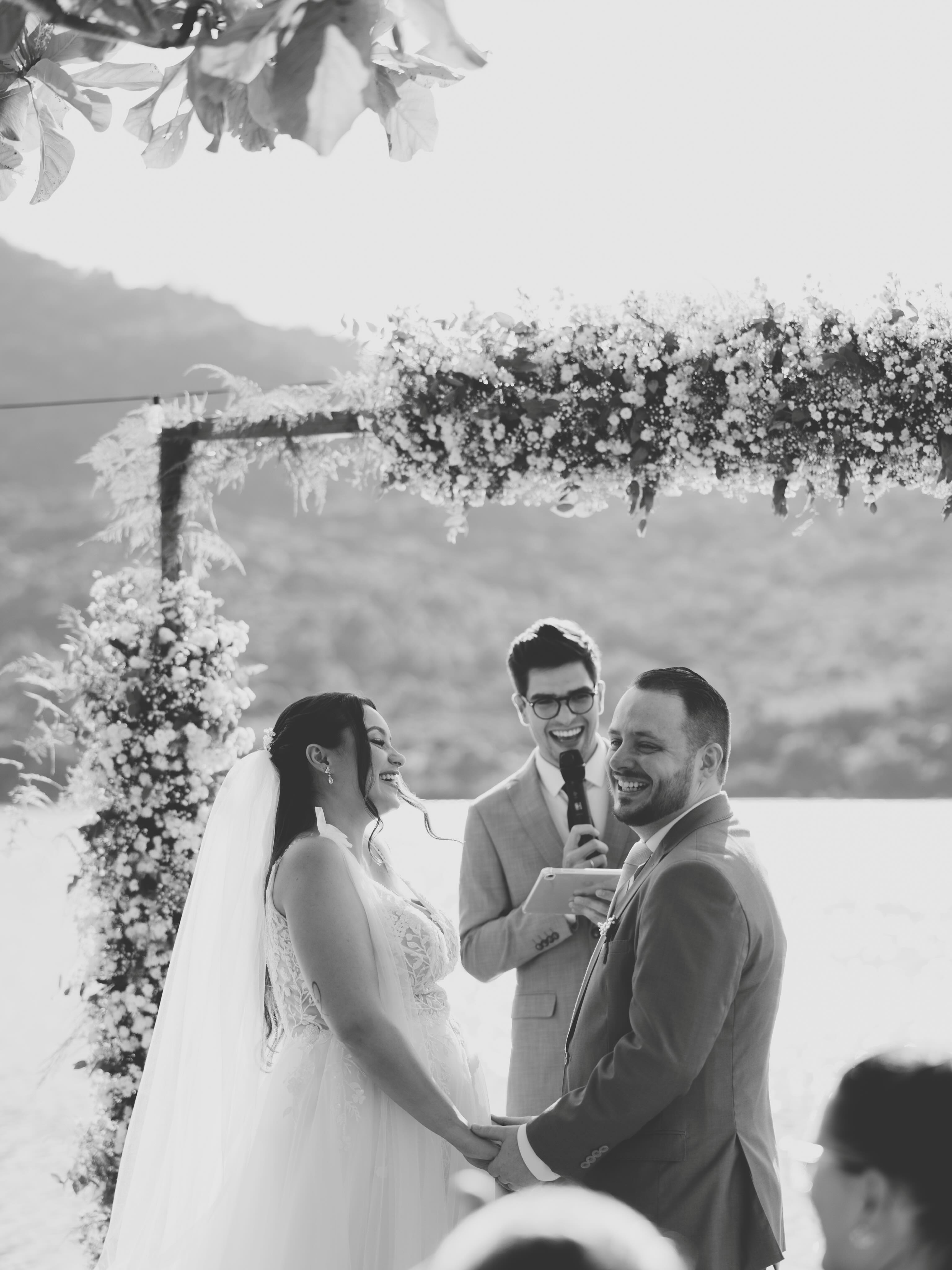 Casal de mãos dadas no altar durante a celebração, em preto e branco